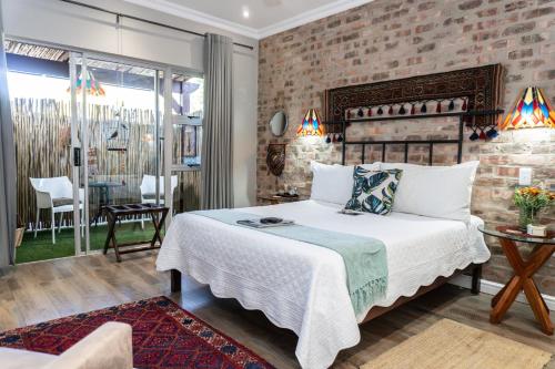 a bedroom with a bed and a brick wall at Earthbound Guest House in Oudtshoorn