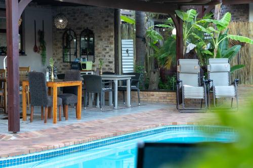a swimming pool with chairs and a table and a restaurant at Earthbound Guest House in Oudtshoorn