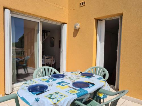- une table avec des plaques et des chaises bleues sur la terrasse dans l'établissement 3 pièces mezzanine CAP D 'AGDE CT200-724, au Cap d'Agde