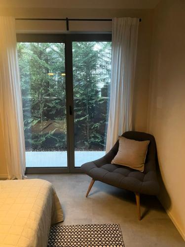 a bedroom with a chair and a large window at Villa LagoBlu in Costermano