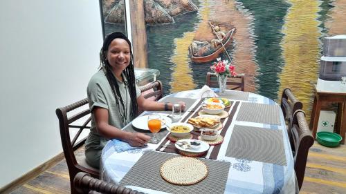 a woman sitting at a table with food on it at SUNSET HILLS in Kandy
