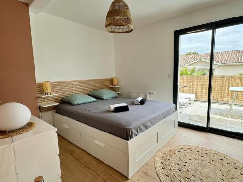 une chambre avec un lit et une grande fenêtre dans l'établissement Joli Appartement avec terrasse Bassin d'Arcachon, à Gujan-Mestras