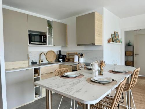 une cuisine avec une table blanche, des chaises et un comptoir dans l'établissement Joli Appartement avec terrasse Bassin d'Arcachon, à Gujan-Mestras