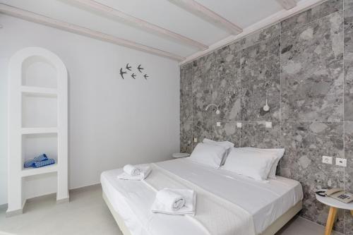 a bedroom with a white bed and a stone wall at Hotel Nathalie in Ixia