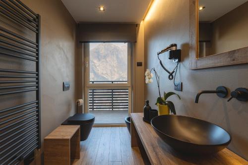 a bathroom with a black bowl sink and a window at Hotel Castel Mani in San Lorenzo in Banale