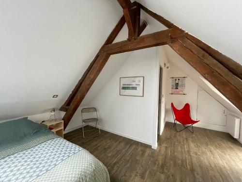 a bedroom with a bed and a red chair at Longère cœur de village proche des plages in Sassetot-le-Mauconduit