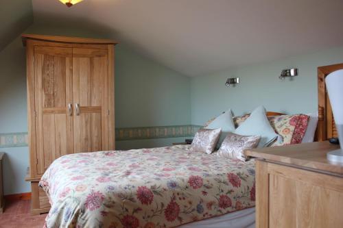een slaapkamer met een bed en een houten kast bij Shiant View in Lochs