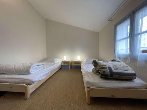 - 2 lits dans une chambre avec une fenêtre et 2 bougies dans l'établissement Maison 4 pièces LA ROCHELLE - LR000-019, à La Rochelle