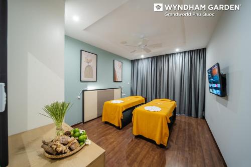a waiting room with two yellow tables and a tv at Wyndham Garden Grandworld Phu Quoc in Phu Quoc