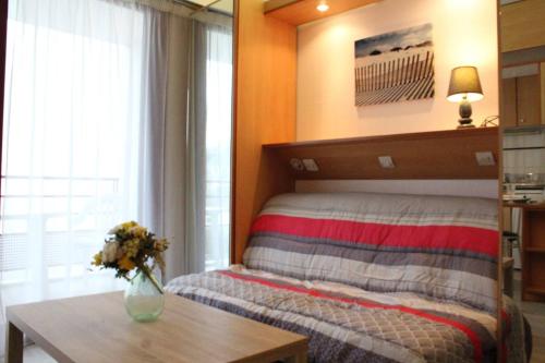 une chambre avec un lit avec une table et un vase de fleurs dans l'établissement Appt Studio LA ROCHELLE - LR010-113, à La Rochelle
