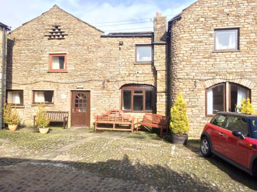 una casa de ladrillo con un coche aparcado delante de ella en The Fox & Hounds Inn, en West Burton