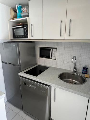 une cuisine avec un évier et un micro-ondes dans l'établissement SAVANNA BEACH I Joli T3 mezzanine vue mer piscine Cap d'Agde, au Cap d'Agde
