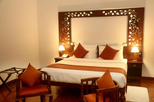 a hotel room with a large bed and two chairs at Villa Mahakanda in Peradeniya