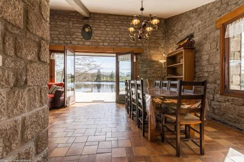 une salle à manger avec un mur en pierre, une table et des chaises dans l'établissement Petit Paradis au coeur du Morvan, à Dun-les-Places