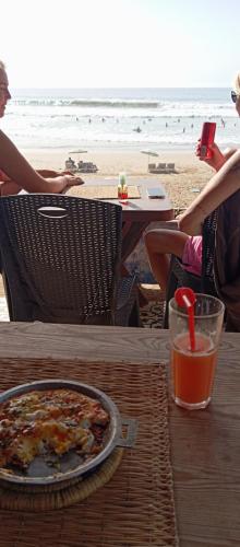 a table with a pizza and a drink on the beach at Appart Oubaha Tamrakht Taghazout Agadir in Agadir