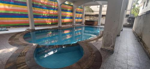 a swimming pool in a building with a colorful wall at Airport villa in Chewarra