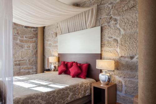 a bedroom with a bed with red pillows at Casas Novas Countryside Hotel Spa & Events in Chaves