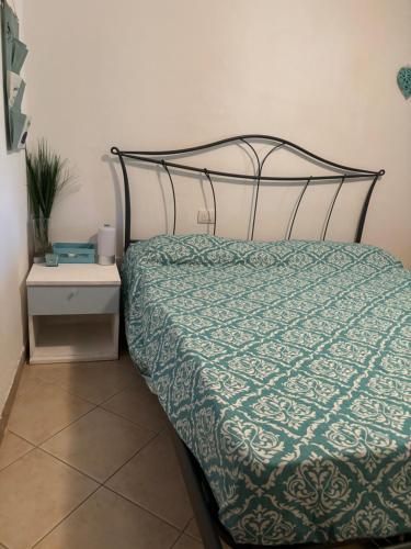 a bed with a green comforter and a night stand at Casa Azzurra in Porto San Paolo