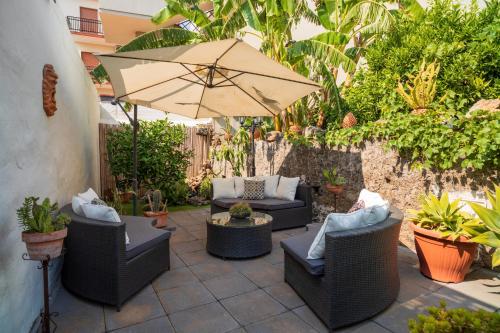a patio with couches and an umbrella at A Ugghia in Fiumefreddo di Sicilia
