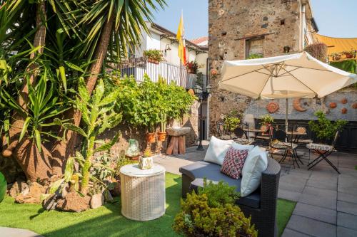 a patio with a couch and an umbrella at A Ugghia in Fiumefreddo di Sicilia