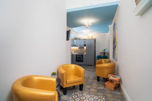a living room with yellow chairs and a kitchen at A Ugghia in Fiumefreddo di Sicilia