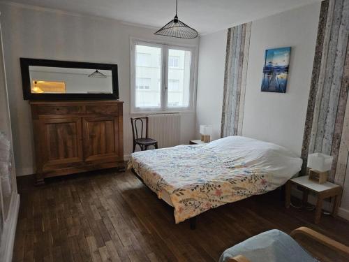 une chambre avec un lit, une commode et un miroir dans l'établissement L'appartement du théatre, à Troyes