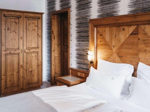 a bedroom with a bed with white sheets and a wooden headboard at Hotel Oberforsthof in Sankt Johann im Pongau
