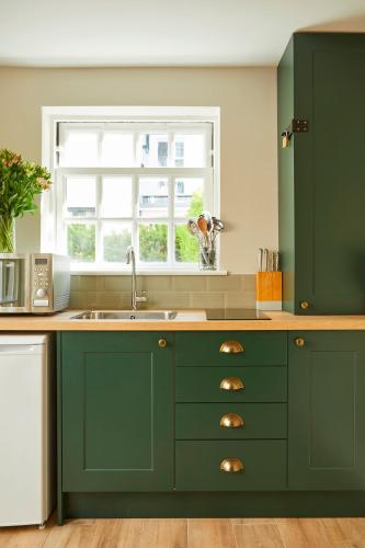 a green kitchen with a sink and a window at Georgian House Hotel in London