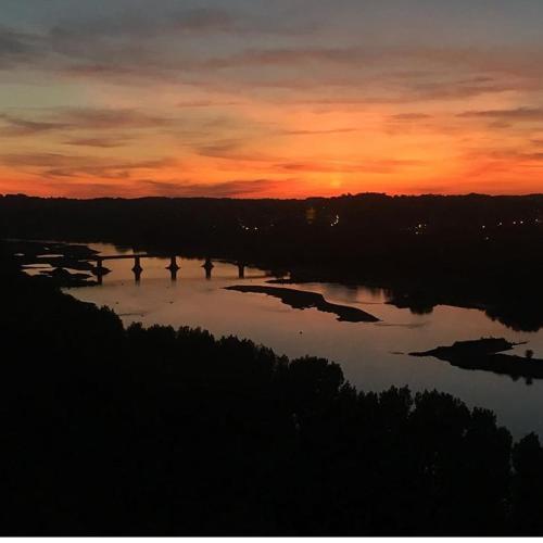 a sunset over a large body of water with trees at Chambre "Les Garennes" in Champtoceaux