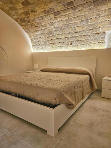a bed in a room with a brick wall at La Stanza di Chiara - Maison à Porter in Vasto