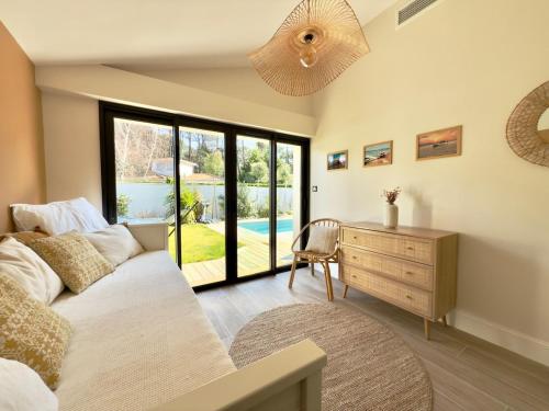 - un salon avec un lit, un bureau et une fenêtre dans l'établissement Sublime maison de vacances piscine au cœur des pins, proche plage, à La Teste-de-Buch