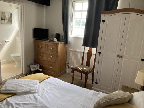 a bedroom with a bed and a dresser and a window at Red Lion in Winfrith Newburgh