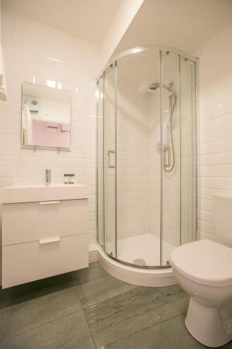 a white bathroom with a shower and a toilet at Pearse Street Gardens in Dublin