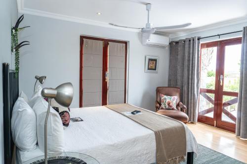 a bedroom with a bed and a chair and a window at Earthbound Guest House in Oudtshoorn