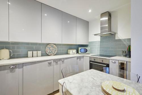a kitchen with white cabinets and a table at Host & Stay - The Courtyard Retreat in Whitby