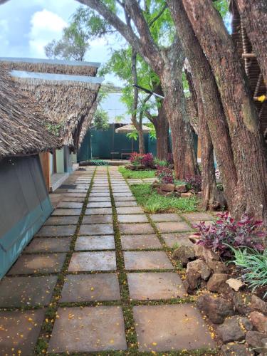 a garden with trees and a stone walkway at The Giraffe Cottages in Nairobi
