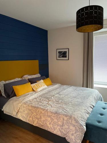 - une chambre avec un grand lit aux murs jaunes et bleus dans l'établissement Le Nid de Cissé, à Cissé