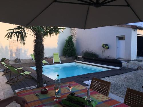 une piscine avec une table et un parasol dans l'établissement Le Nid de Cissé, à Cissé