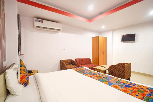 a room with a bed and a table and chairs at FabExpress R Inn - Nr Prayagraj Railway Station in Muthiganj