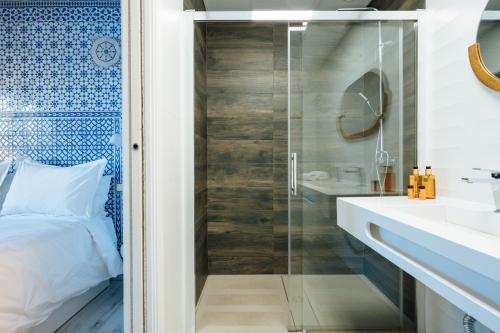 a bathroom with a glass shower and a bed and a sink at Apartamentos "El Escondite de Triana" in Seville