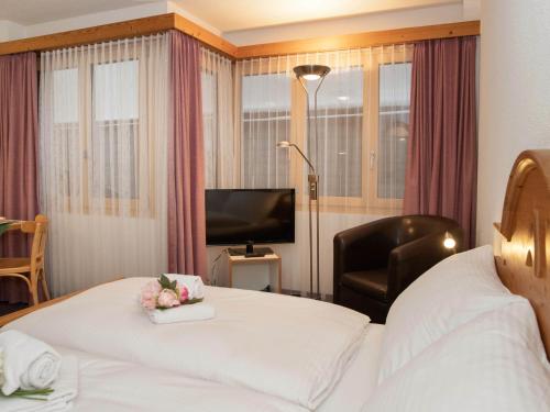 a hotel room with a bed and a chair and a television at Apartment Chalet Abendrot apARTments-3 by Interhome in Grindelwald