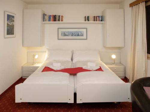 a white bed in a room with two tables at Apartment Chalet Abendrot apARTments-6 by Interhome in Grindelwald
