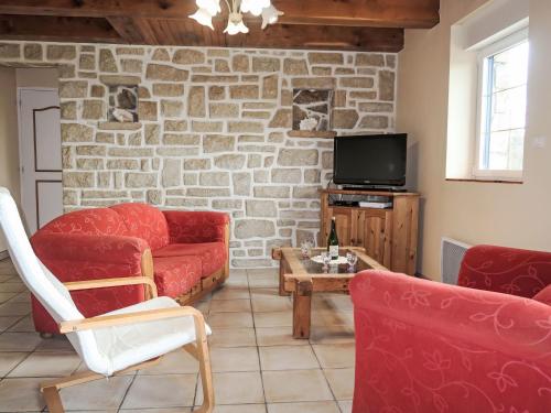Elle comprend un salon doté d'un mobilier rouge et d'un mur en pierre. dans l'établissement Holiday Home Milin-Avel by Interhome, à Telgruc-sur-Mer