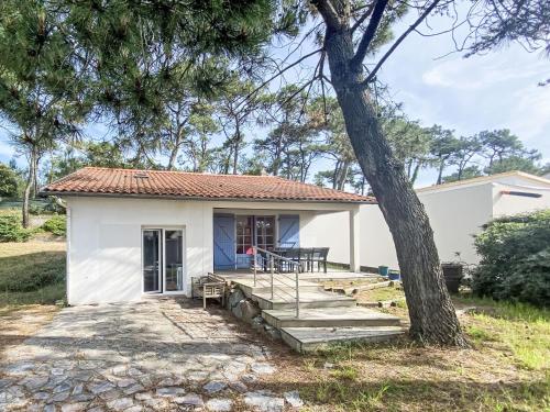 a small white house with a porch and a tree at Holiday Home Les Rougets by Interhome in La Tranche-sur-Mer