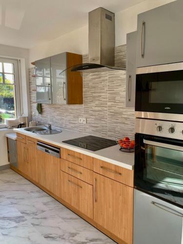 une cuisine avec des appareils en acier inoxydable et des armoires en bois dans l'établissement Appartement à Cancale situé à 500 m du port, à Cancale