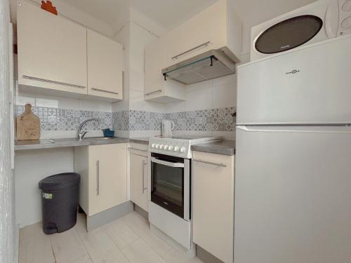 La cuisine blanche est équipée d'un évier et d'un réfrigérateur. dans l'établissement Charmant studio bohème vue dégagée moderne, à Fréjus