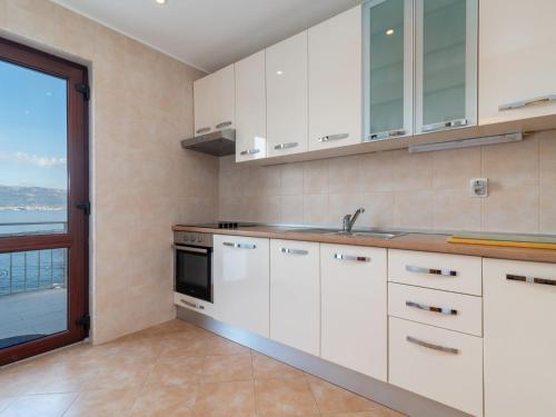a kitchen with white cabinets and a large window at Holiday Home Robert by Interhome in Trogir