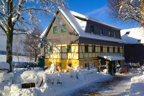 a house covered in snow in front at Hotel Olbernhau mit Sauna - Kleines Landhotel zur Ofenschenke in Olbernhau