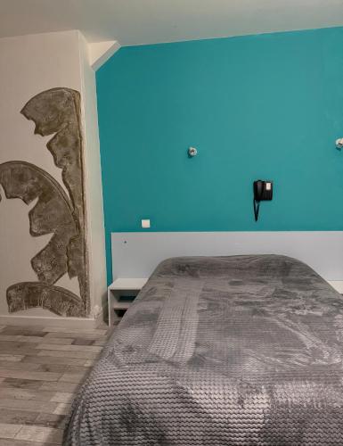a bedroom with a bed with a blue wall at Le Relais de la route bleue in Saint-Loup