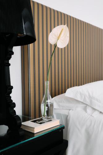 a flower in a vase on a table next to a bed at Palazzo del Corso – Boutique Hotel in Gallipoli